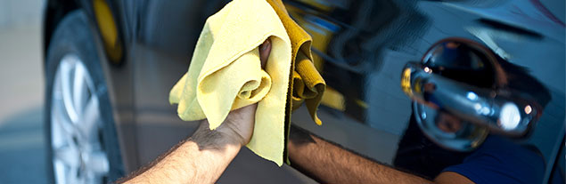 Person drying a car with a towel.